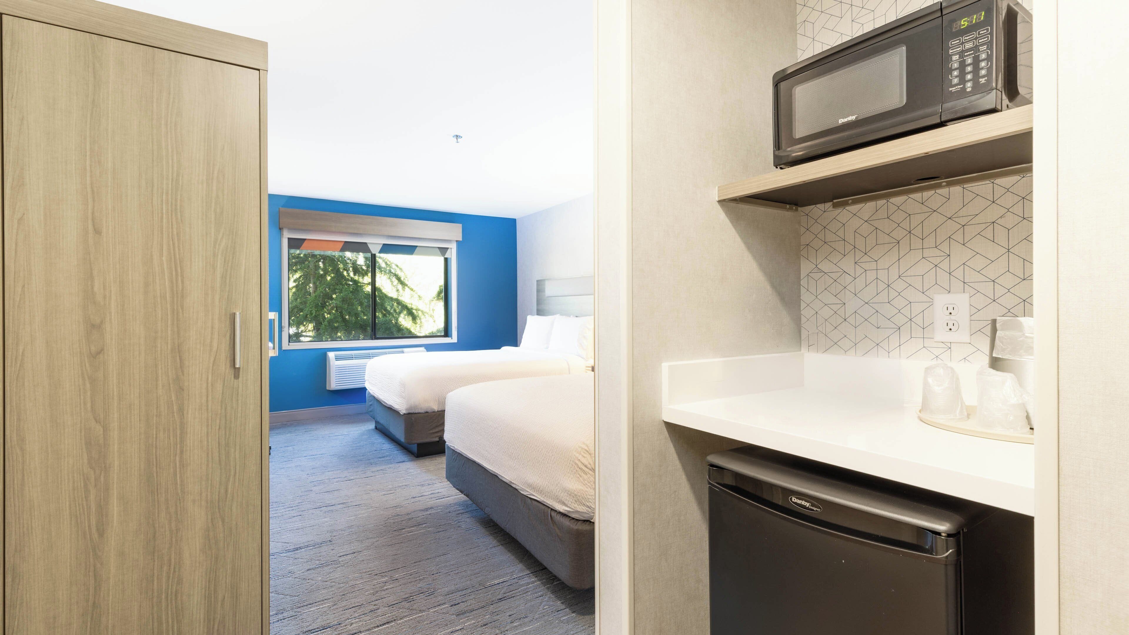 Habitación de hotel con cama, microondas y lavavajillas.