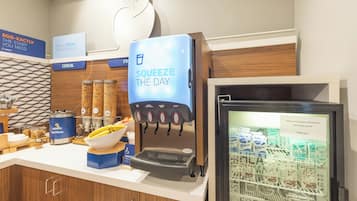 A breakfast station with a coffee machine, cereal dispensers, and a refrigerated display of dairy products.
