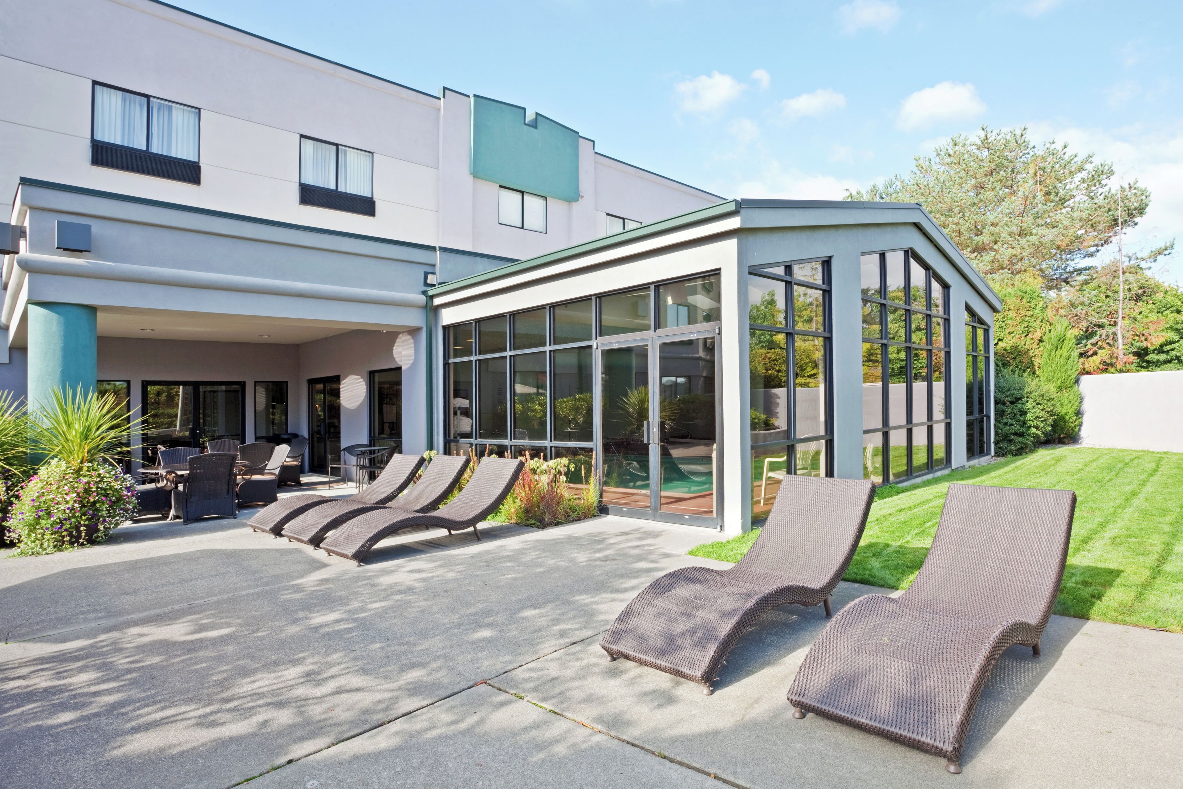 A modern building with a covered outdoor seating area and a glass enclosure.