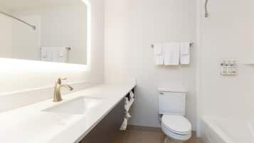 Un baño moderno con lavamanos, espejo, inodoro y toallero.
