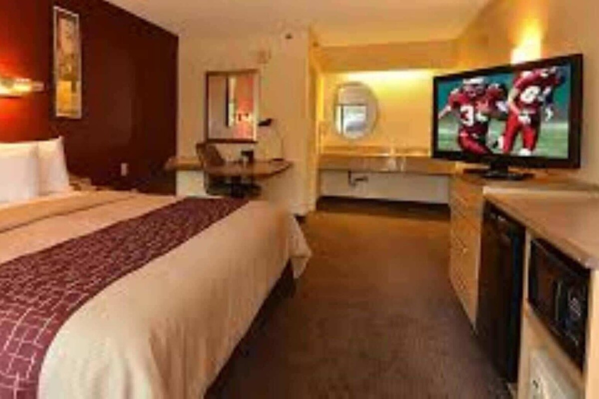 A hotel room with a bed, a desk, a television, and a bathroom.