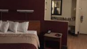 Una habitación de hotel con una cama, una mesita de noche y un pequeño escritorio con una silla.