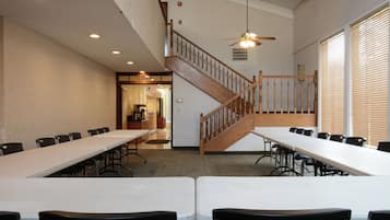 A conference room with long tables and chairs, a wooden staircase, and a ceiling fan.