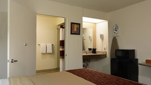 Habitación de hotel con cama, baño con ducha, secador de pelo y microondas.