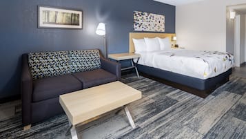 A hotel room with a bed, a sofa, a small table, and a nightstand.