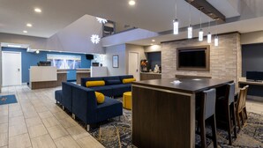 A modern hotel lobby with a seating area, a kitchen, and a bar. - Baymont by Wyndham White Plains - Elmsford (Elmsford)