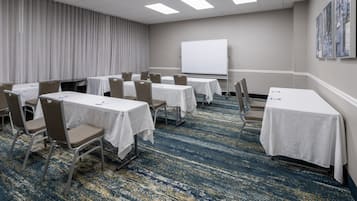 Una sala de conferencias con mesas, sillas, una pizarra y suelo alfombrado.