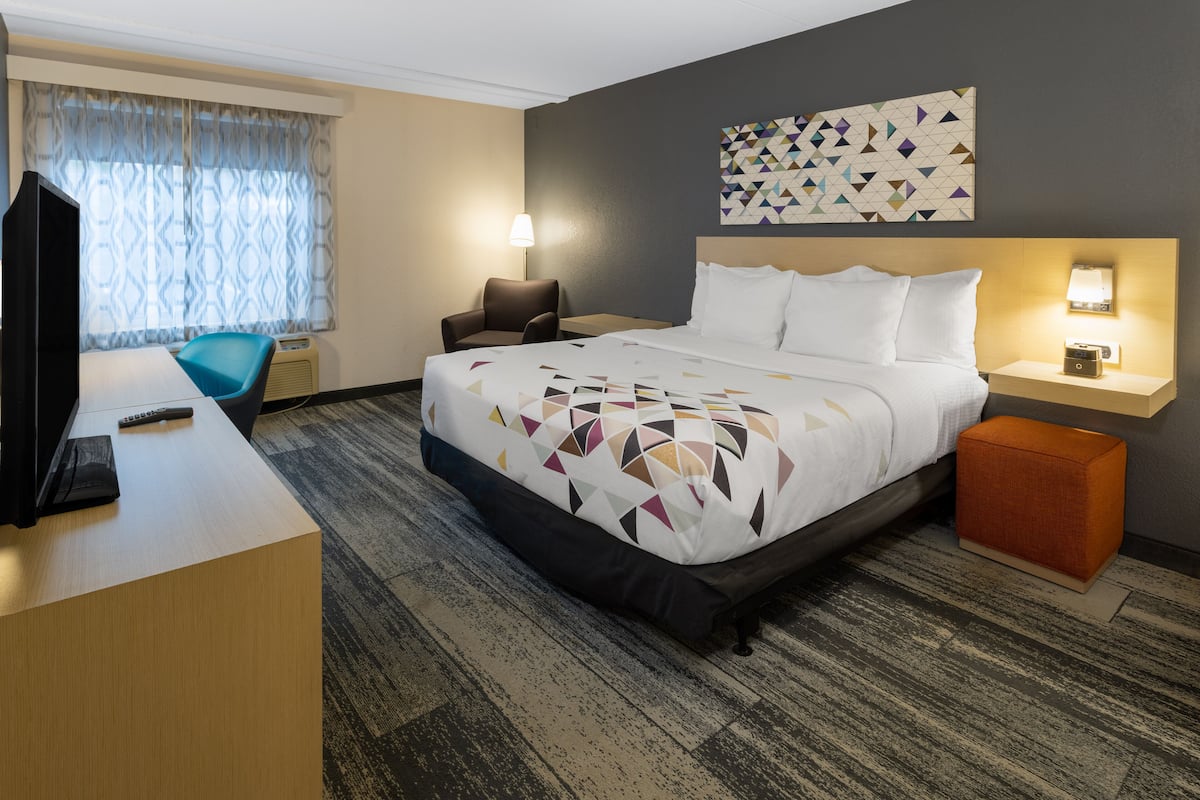 Ein Hotelzimmer mit Bett, Schreibtisch, Stuhl, Fernseher und Lampe.