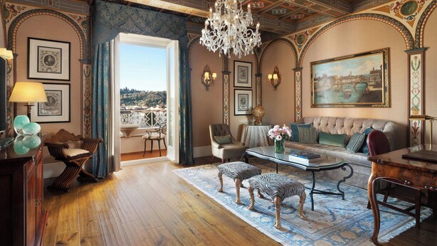 A spacious room with a large window, a chandelier, and a sofa.