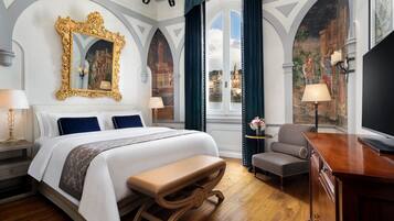 Ein luxuriöses Hotelzimmer mit einem großen Bett, einer Bank, einem Schreibtisch und Blick auf die Skyline der Stadt.