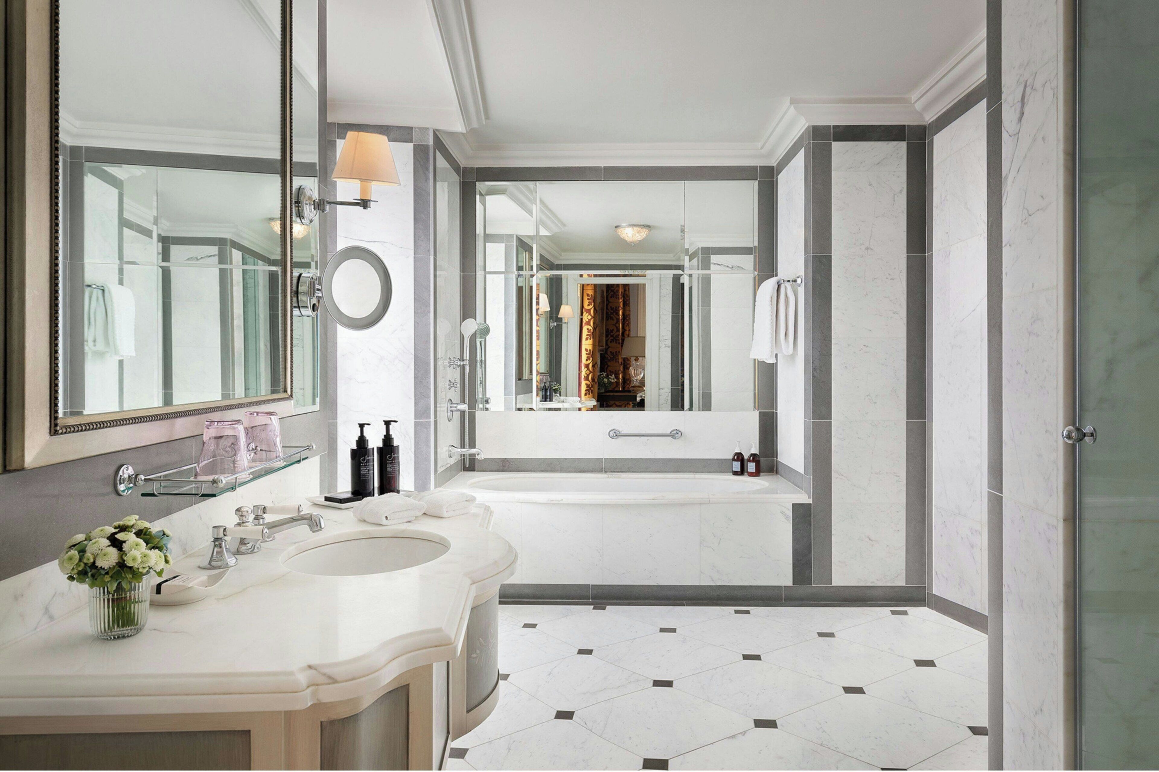 Un baño moderno con un espejo grande, dos lavamanos, una bañera y una zona de ducha.