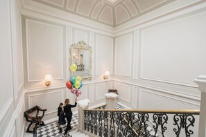 A grand staircase with ornate black iron railings and a checkered floor.