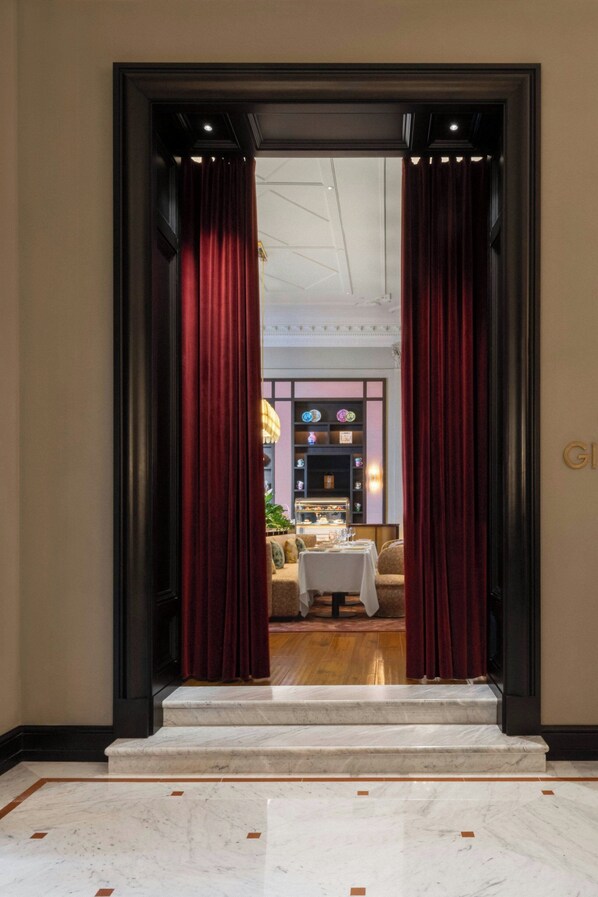 Un vestíbulo de hotel con una escalera de mármol que conduce a un comedor.