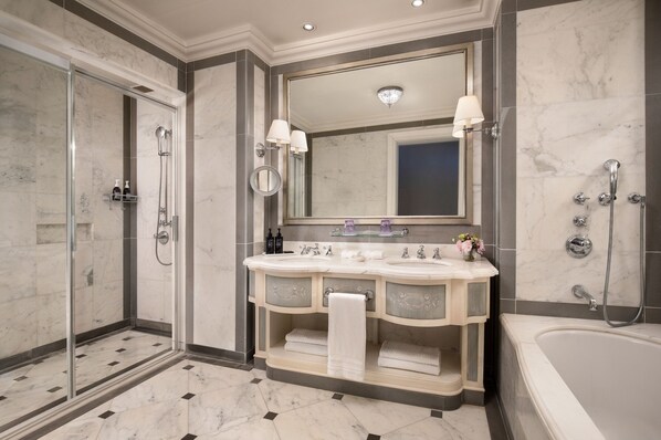 A modern bathroom with a glass-enclosed shower, dual sinks, a large mirror, and a bathtub.