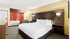 A hotel room with a large bed, a desk, a chair, a nightstand, and a wall-mounted lamp. - Quality Inn Mount Vernon (Mount Vernon)