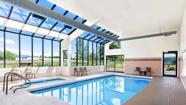 A modern indoor swimming pool with large windows, a clear view of the outdoors, and a simple seating area. - Quality Inn Mount Vernon (Mount Vernon)
