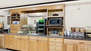 A kitchen with wooden cabinets, a microwave, a coffee machine, and various food items on the counter. - Quality Inn Mount Vernon (Mount Vernon)