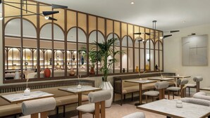 Un restaurant moderne avec des banquettes, des tables et un mur décoratif agrémenté d’arches.