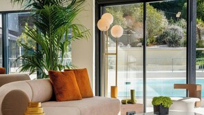 Un salon moderne avec un canapé, une table basse et une grande fenêtre donnant sur une piscine.