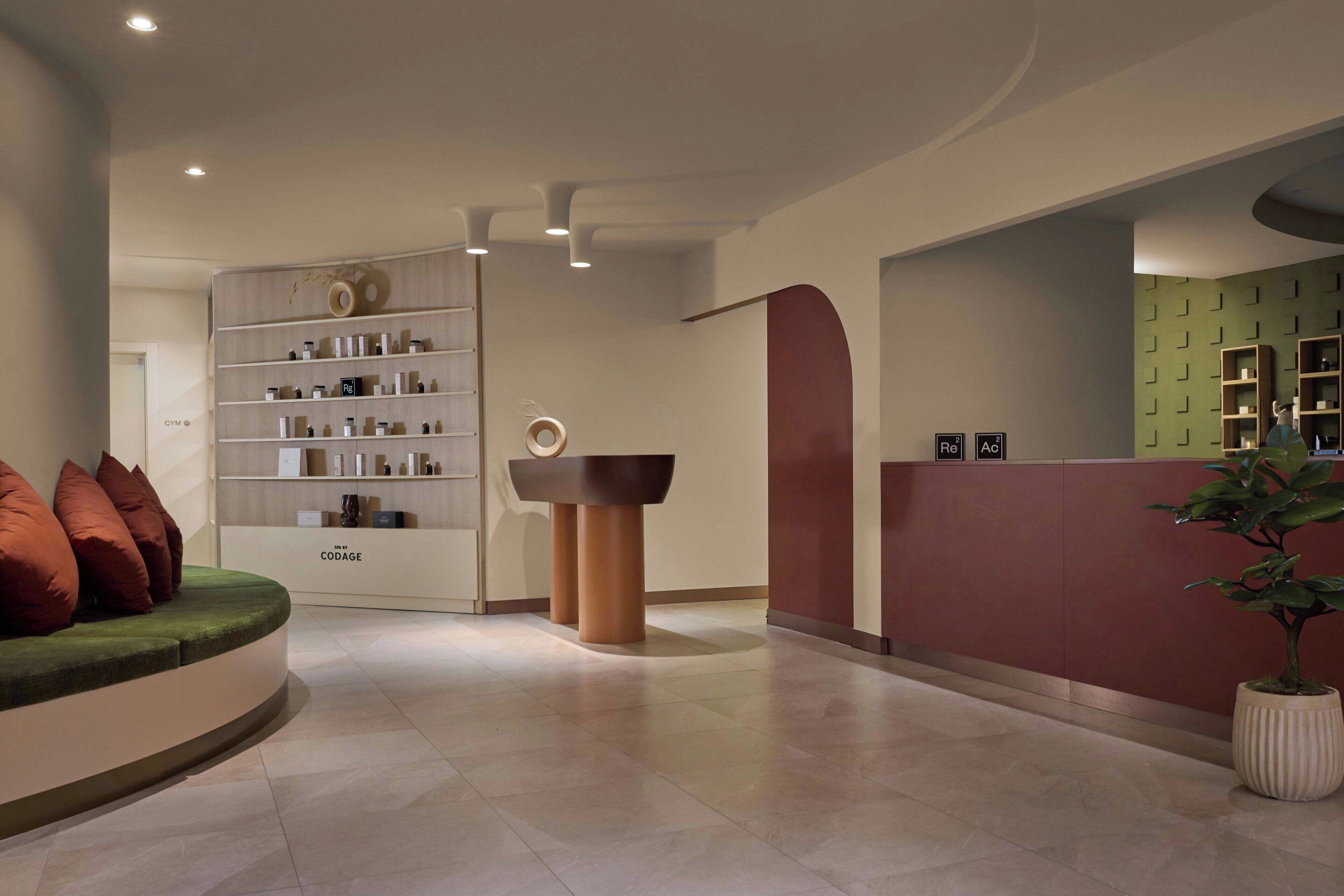 A modern reception area with a curved seating area, a reception desk, and a wall-mounted shelf with various items.
