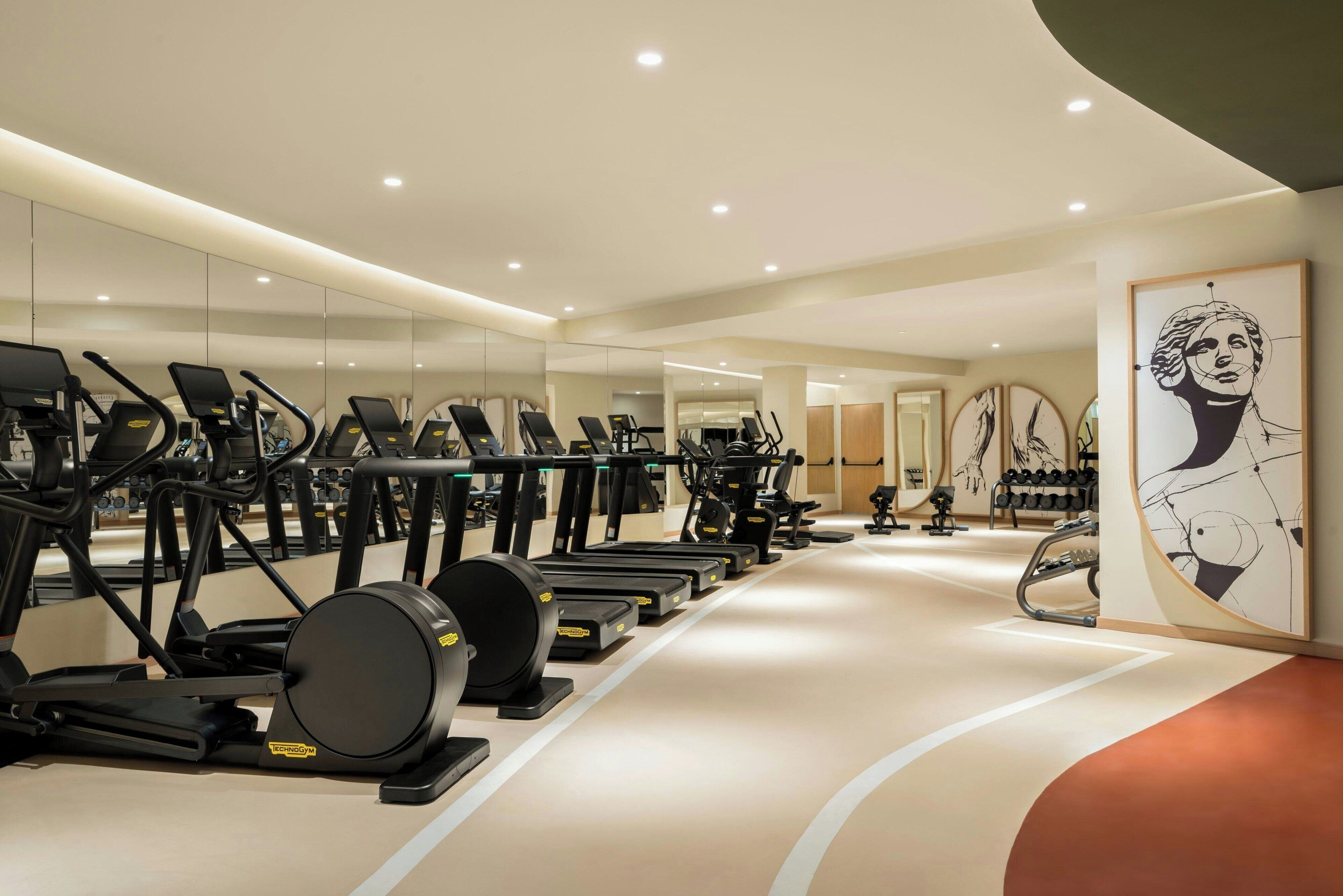 Ein modernes Fitnessstudio mit mehreren Laufbändern, Ergometer und Kraftgeräten.