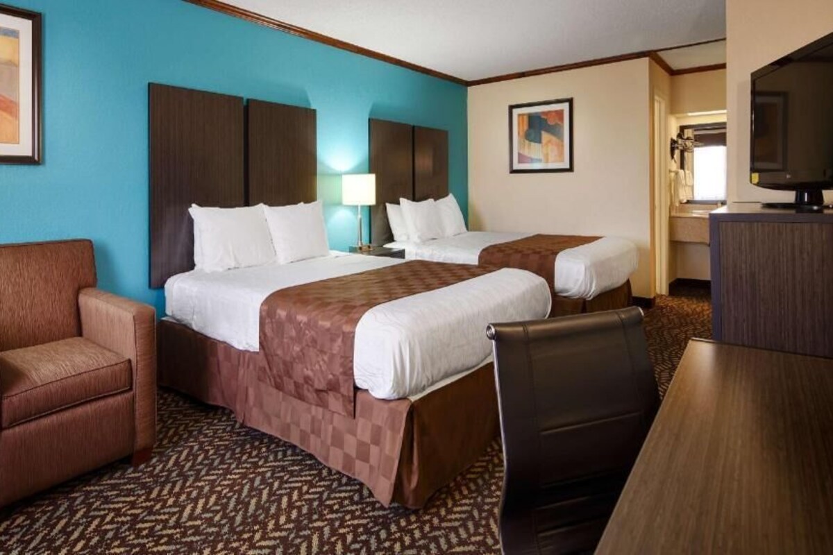 Une chambre d’hôtel avec deux lits, un bureau, une chaise et un téléviseur.