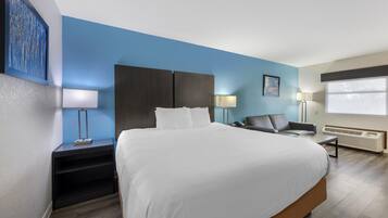 Una habitación de hotel con una cama grande, un escritorio, una silla, una lámpara y una ventana.