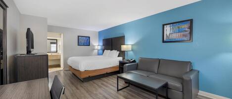 Ein modernes Hotelzimmer mit Bett, Sofa, Schreibtisch und Fernseher.