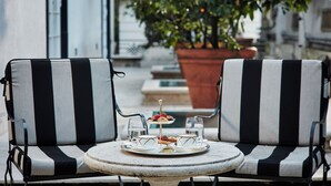 A round table with two chairs, a tray with food and drinks, and a potted plant in the background. - Hotel Lord Byron (Rome)