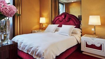 A hotel room with a large bed, two bedside tables with lamps, a mirror, and a vase with flowers.
