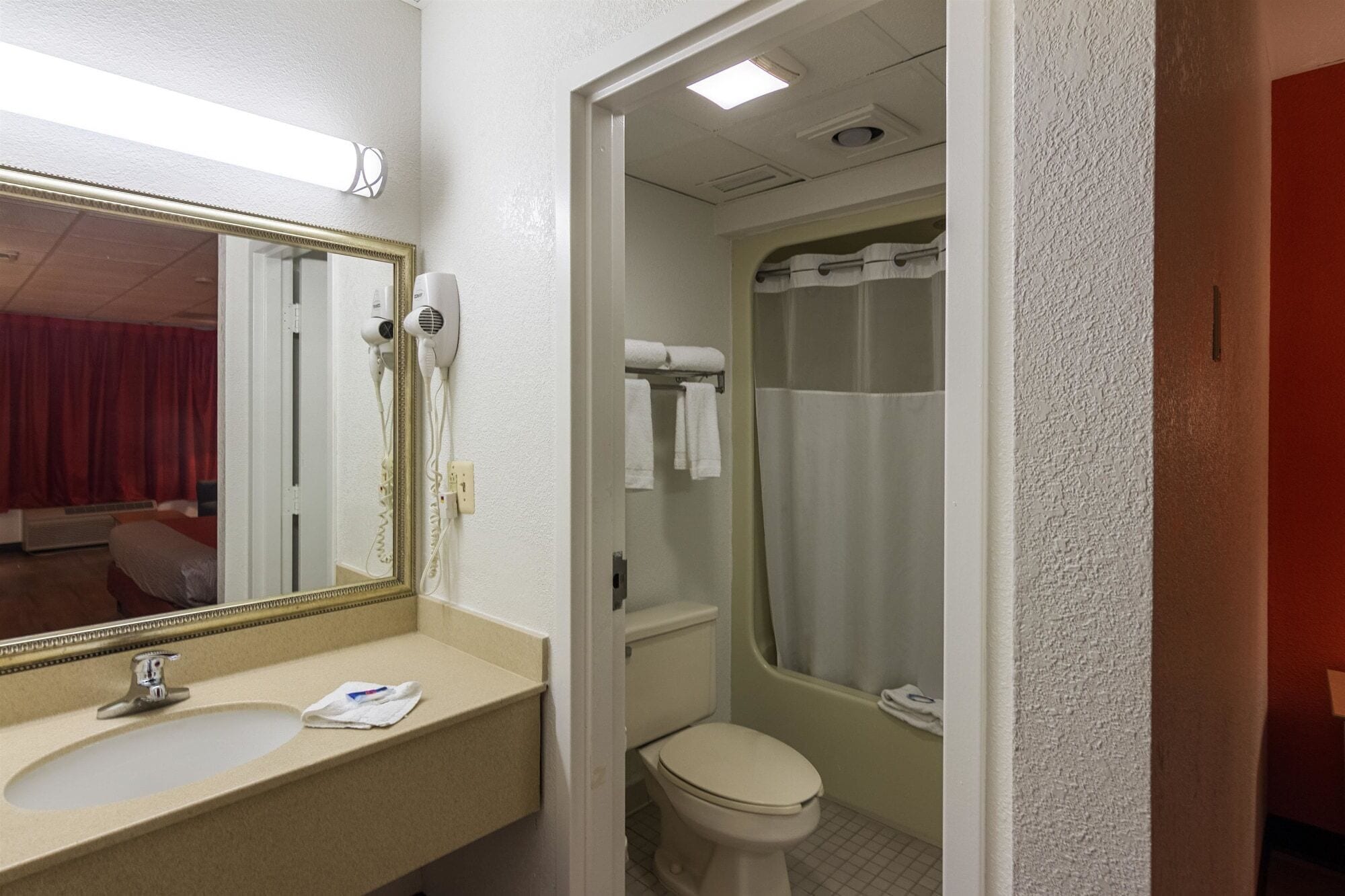 A bathroom with a sink, mirror, and two hair dryers mounted on the wall.