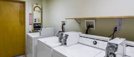 A laundry facility with multiple washing machines and dryers, a fire extinguisher, and a laundry bar.