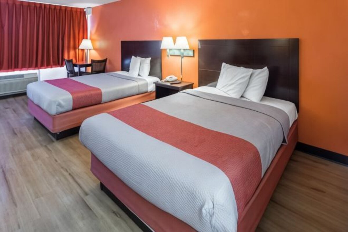 A hotel room with two beds, a desk, and a chair.