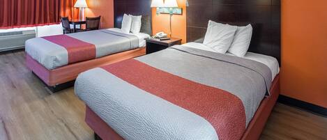 A hotel room with two beds, each with a headboard, bedside lamps, and a telephone on the nightstand.