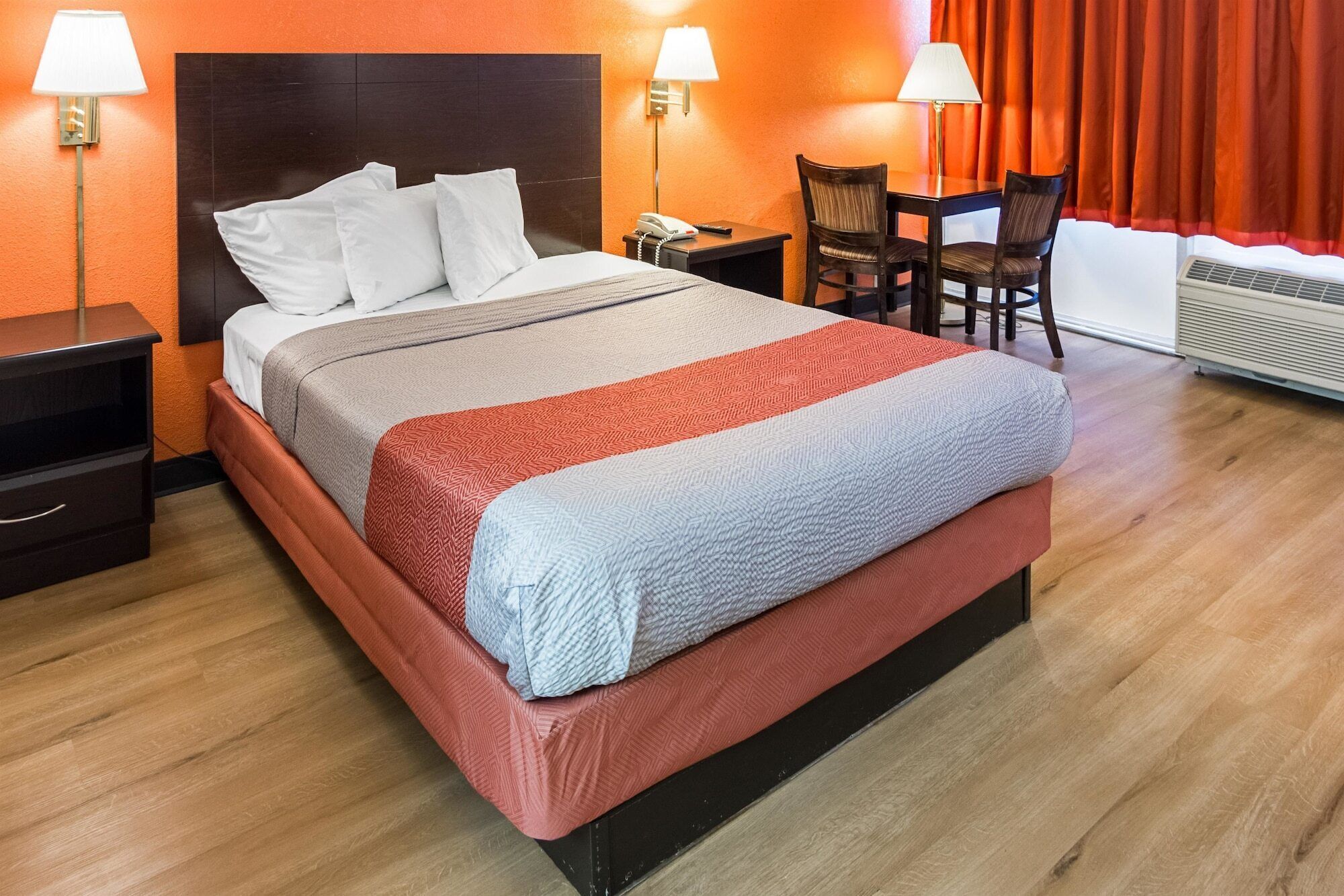 Une chambre d’hôtel avec un lit, des tables de chevet, un bureau et une chaise.