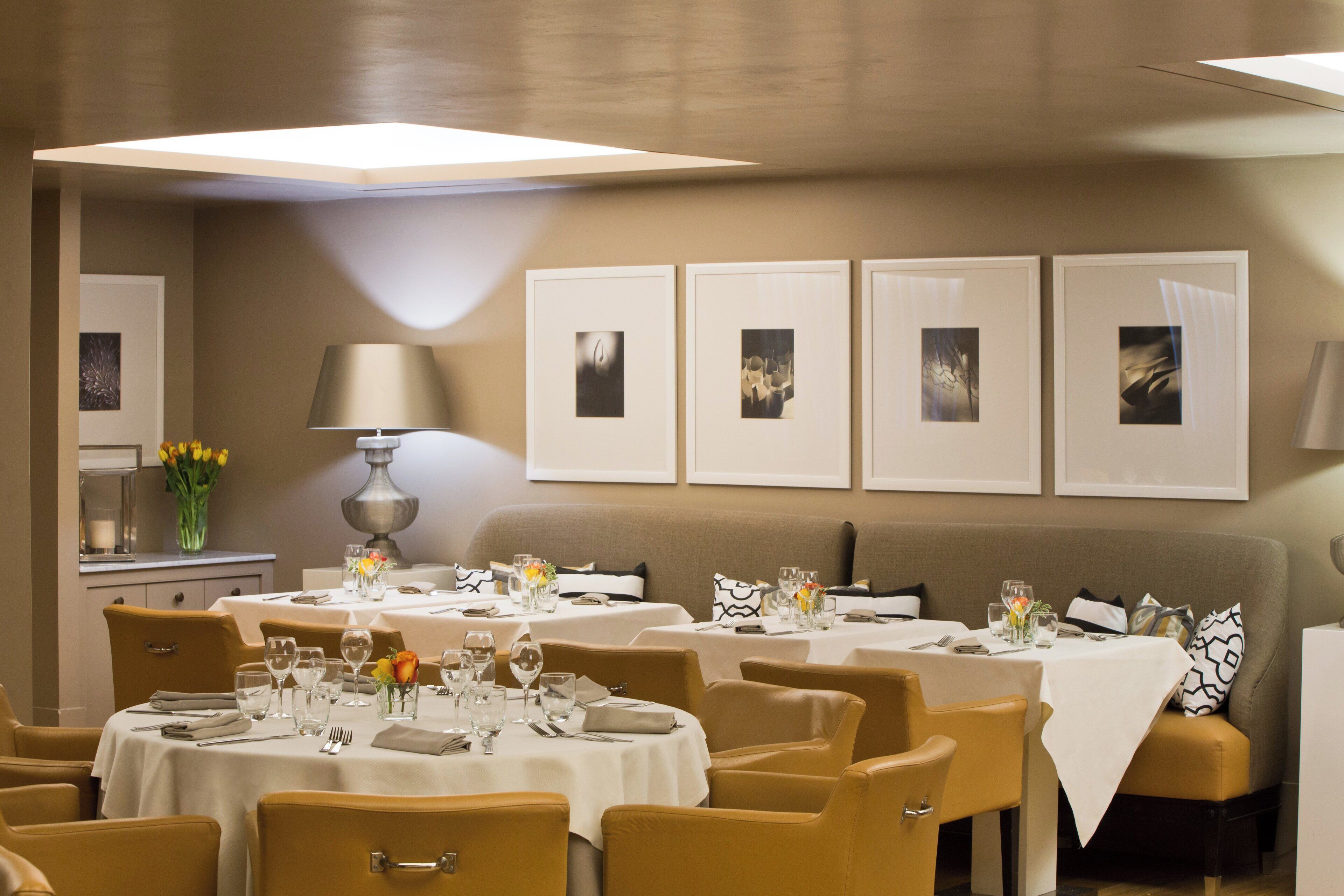 A restaurant with tables set for dining, framed artwork on the walls, and a modern interior design.