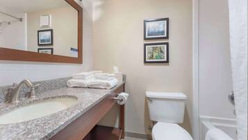 A bathroom with a granite sink, white toilet, and a shower curtain.
