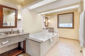 A modern bathroom with a large bathtub, two sinks, and a vanity.