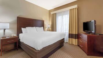 A hotel room with a large bed, a TV, a nightstand, and a dresser.