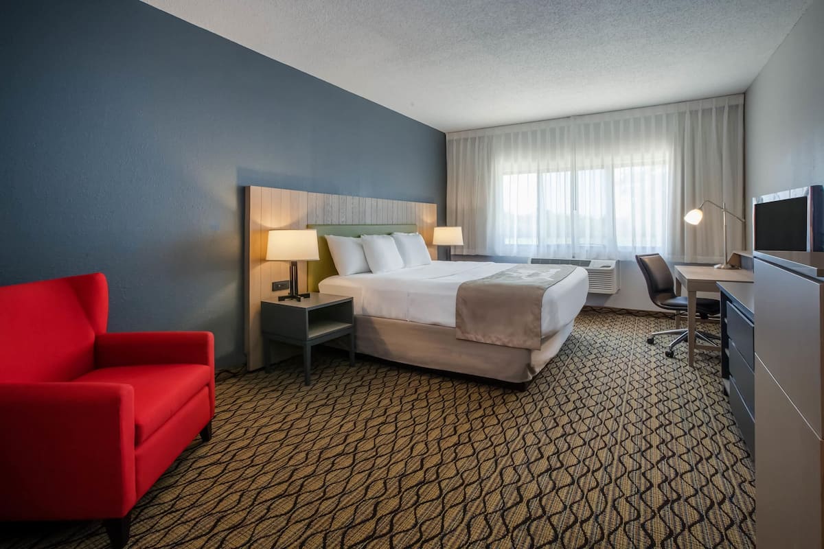 A hotel room with a bed, a desk, a chair, and a TV.