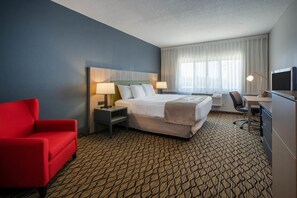 A hotel room with a bed, a desk, a chair, and a TV.