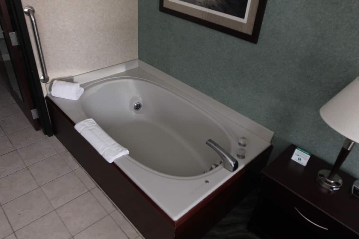 A bathroom with a bathtub, a towel, a sink, and a mirror.