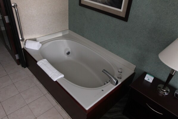 A bathroom with a bathtub, a towel, a sink, and a mirror.