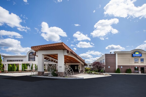 A Days Inn 6 Suites building with a covered entrance and a fountain.