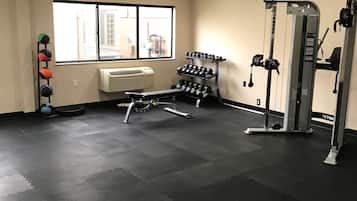 Un gimnasio con equipo de ejercicio, una ventana y un aire acondicionado instalado en la pared.
