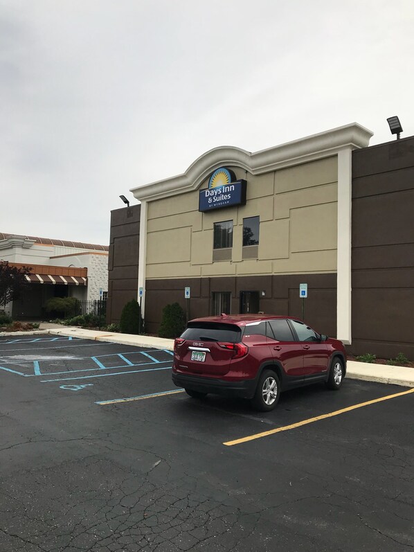 A Days Inn & Suites building with a parking lot and a maroon SUV parked in front.