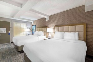 A hotel room with two beds, a brick wall, a ceiling with exposed beams, and a door with a sign. - Best Western Savannah Historic District (Savannah)