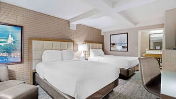 A hotel room with two beds, a desk, a chair, and a large window.