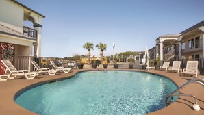 A swimming pool with lounge chairs and a building with balconies in the background. - Best Western Inn (Florence)