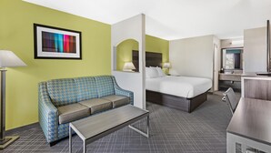 A hotel room with a checkered sofa, a bed, a desk, and a framed picture on the wall. - Best Western Inn (Florence)